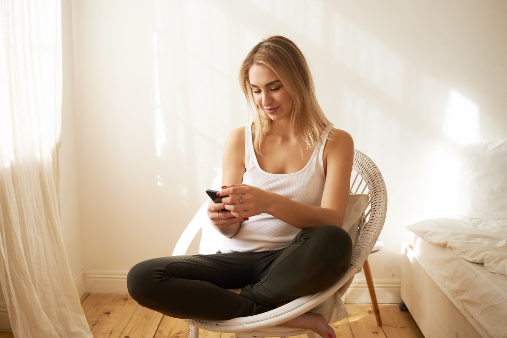 cute-teen-girl-sitting-in-comfortable-armchair-in-her-bedroom-holding-cell-phone-messaging-friends-online-making-plans-for-weekend-adorable-young-female-surfing-internet-via-mobile-using-wifi.jpg