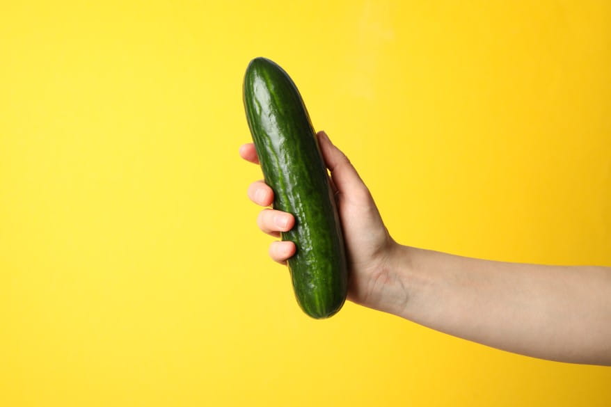 female-hand-holding-cucumber-on-yellow-surface.jpg